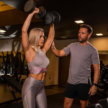 Five Jumeirah Village Dubái Exterior foto Personal trainer assisting a woman with a dumbbell press